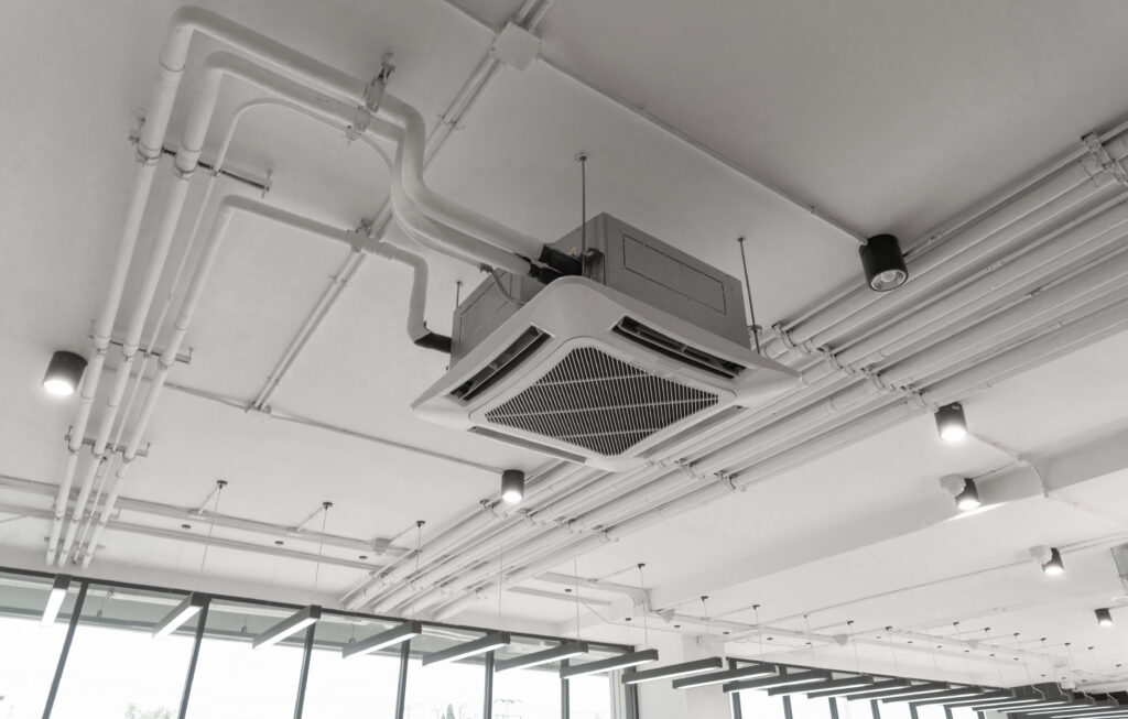 Modern white ceiling mounted cassette type air conditioner in office building system work. Ventilation compressor.